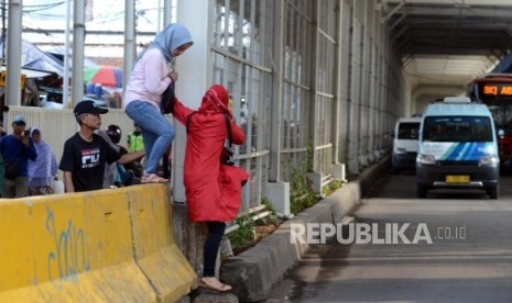 Warga melintasi pagar beton pembatas jalan di Jalan Jatibaru, Tanah Abang, Jakarta, Rabu (9/1).