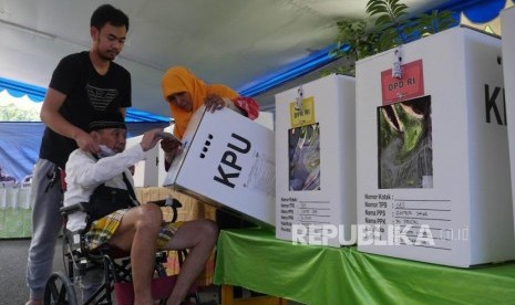 Seorang pemilih lansia dibantu petugas KPPS memasukkan surat suaranya kedalam kotak suara di TPS 65, kelurahan Sunter Jaya, Jakarta, Rabu (17/4).