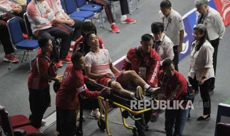 Pebulutangkis Indonesia Anthony Sinisuka Ginting ditandu keluar lapangan seusai mengalami cidera pada pertandingan final cabang bulutangkis nomor beregu putra Asian Games 2018 melawan Cina di Stadion Istora Senayan, Jakarta, Rabu (22/8).