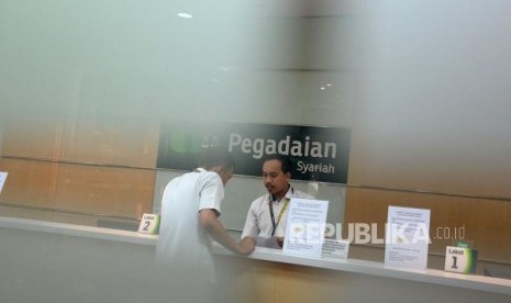 Petugas melayani nasabah ketika bertransaksi di kantor pelayanan Pegadaian Syariah, Jakarta, Jumat (4/1).