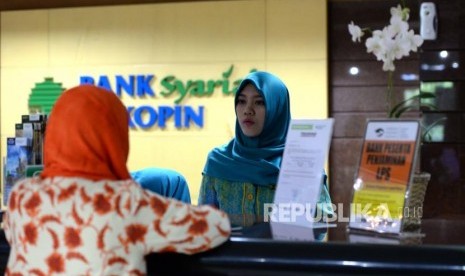 Petugas melayani transaksi nasabah di kantor layanan Bank Syariah Bukopin, Jakarta, Selasa (2/1).