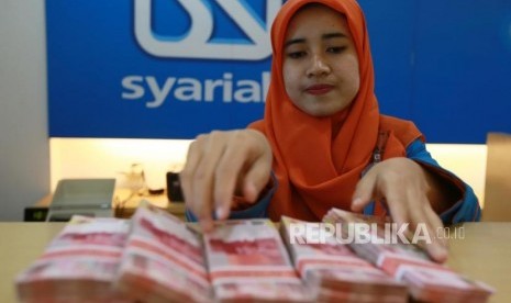 Petugas menghitung uang rupiah di Banking Hall Bank BRI Syariah, Jakarta, Kamis (30/11).