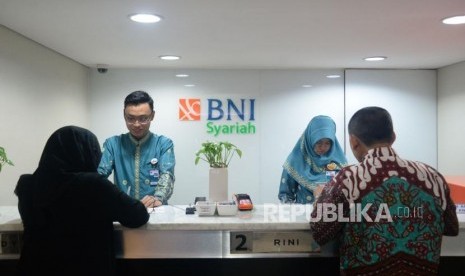 Petugas melayani transaksi nasabah di kantor layanan BNI Syariah, Jakarta,Kamis (1/2).