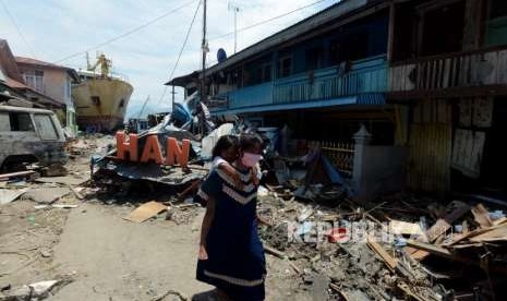 Sejumlah warga berjalan didekat bangunan yang runtuh di Pelabuhan Wani, Palu, Sulawesi Tengah, Kamis (4/10).