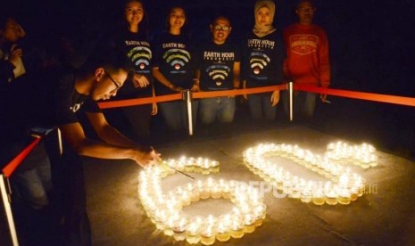 Sejumlah aktivis dari Eart Hour menyalakan lilin saat listrik dipadamkan pada acara gelaran tahunan Earth Hour 2018, di kawasan Gedung Sate, Kota Bandung, Ahad (25/3).