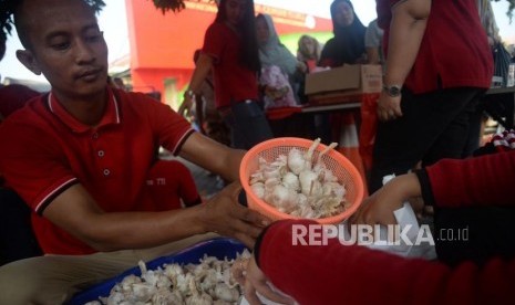 Petugas menimbang bawang putih ketika gelar pangan murah berkualitas di Toko Tani Indonesia Center, Jakarta, Ahad (5/5).