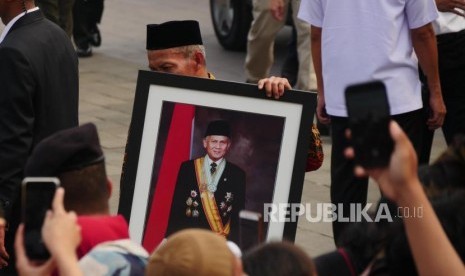 Seorang petugas membawa foto Presiden Ketiga RI BJ Habibie pelataran Taman Makam Pahlawan Kalibata, Jakarta, Kamis (12/9).