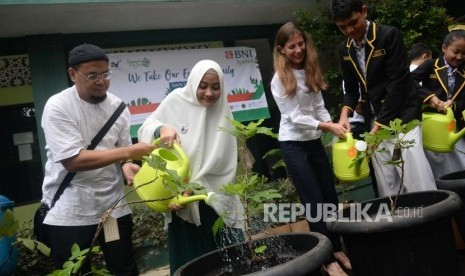 Coorporate Sekretary BNI Syariah Rima Dwi Permatasari (kedua kiri) bersama Bendahara Badan Wakaf Indonesia Rahmad (kiri), Vice President UNDP Indo Francine (kedua kanan) dan para pelajar menyiram tanaman pada kegiatan program Hasanah Earth Day bertajuk we take our earth seriously di SMPN 19 Jakarta, Kamis (19/4). 