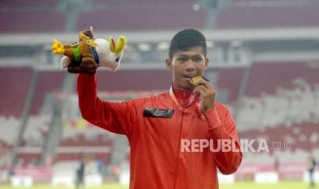 Sprinter Indonesia Sapto Yogo Purnomo menggigit medali   usa penyerahan medali emas  final 100 meter putra T37 Asian Para Games di Stadion Utama Gelora Bung Karno, Senayan, Jakarta, Selasa  (9/10).