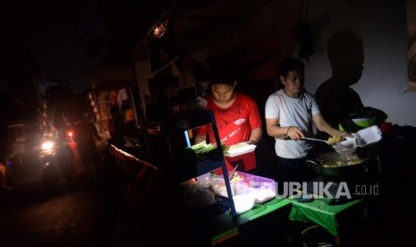 Pedagang melayani pembeli ketika terjadinya pemadaman listik di kawasan pemukiman padat penduduk Karet Tengsin, Jakarta, Ahad (4/8).