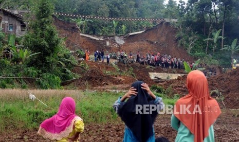 Warga menyaksikan petugas gabungan melakukan evakuasi pencarian korban longsor di Kampung Maseng, Cijeruk, Kabupaten Bogor, Jawa Barat, Selasa (6/2).