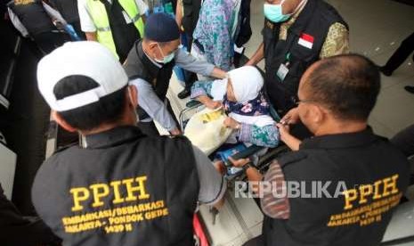 Petugas membantu Jamaah Haji Indonesia Kloter 19 Debarkasi Jakarta Pondok Gede (JKG) menaiki kursi roda saat tiba di Asrama Haji Pondok Gede, Jakarta, Rabu (5/9).