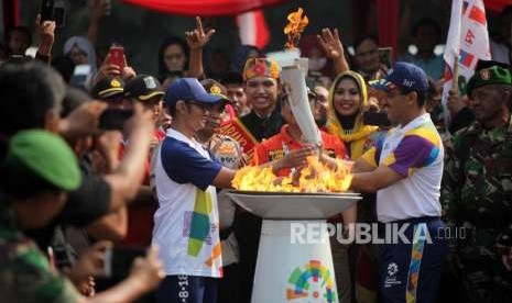 Walikota Jakarta Timur M. Anwar (kanan) menyerahkan obor Asian Games kepada Atlet taekwondo Priyaka Irfan Astama Harsono (kiri) saat Torch Relay Asian Games 2018 di Kawasan Kramat Jati, Jakarta, Rabu (15/8).