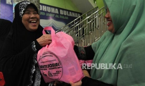 Warga menerima bantuan bakti sosial di Masjid Jami Al Falah, Menteng, Jakarta Pusat, Ahad (17/12).