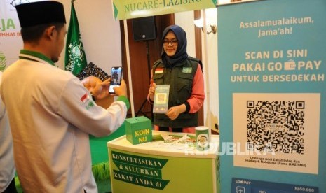 ZIS Digital Nahdliyin memindai QR Barcode untuk pembayaran zakat, infak dan sedekah secara non tunai melalui Go-Pay dalam peluncuran Kerjasama Strategis Pemberdayaan Ekonomi Umat berbasis Digital antara Gojek, Go-Pay dengan NU Care LazisNU di Jakarta, Selasa (16/7).