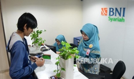 Karyawan melayani transaksi nasabah di kantor layanan BNI Syariah, Jakarta, Selasa (22/1).