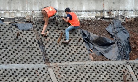 Pekerja menyelesaikan proyek normalisasi Sungai Ciliwung di Bukit Duri, Jakarta.