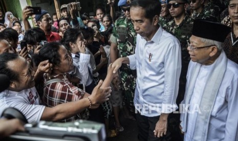 Capres Petahana Joko Widodo (tengah) bersama Cawapres Ma’ruf Amin (kanan) menyapa warga usai pidato kemenangan sebagai Presiden periode 2019-2024 di Kampung deret,Tanah tinggi,Johor baru, Jakarta Pusat, Selasa (21/5).