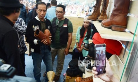 Presiden RI Joko Widodo (Jokowi) mengamati produk sepatu kulit pada pameran Komunitas Kreatif, di Jalan Braga, Kota Bandung, Ahad (11/11).