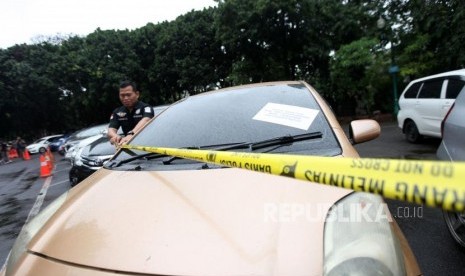 Petugas polisi memasang garis polisi barang bukti kendaraan mobil saat rilis kasus kendaraan bermotor di Polda Metro Jaya, Jakarta, Ahad (26/11).