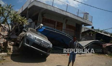 Warga  berada di depan mobil dan rumah yang rusak  akibat gempa, Desa Pemenang, Lombok Utara, NTB, Rabu (8/8).