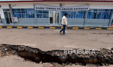 Warga melintas didekat area parkir ruang tunggu yang retak akibat gempa di Pelabuhan Kayangan, Lombok Timur, NTB, Selasa (21/8).