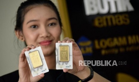 Karyawan menunjukan emas batangan di Butik Emas Logam Mulia ANTAM. Harga emas batangan Antam Sabtu (6/1/2023) pagi naik Rp3.000.