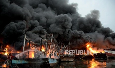 Sejumlah petugas pemadam kebakaran dibantu warga berusaha memadamkan kapal yang terbakar di Pelabuhan Muara Baru, Jakarta, Sabtu (23/2).