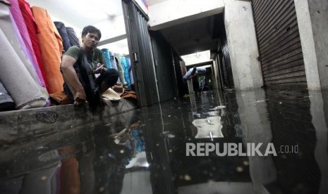 Pedagang menunggu duduk dikiosnya saat air menggenangi Pasar Blok G Tanah Abang, Jakarta, Senin (11/12).