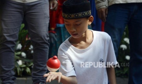 Anak-anak bermain gangsing pada acara Festival Permainan Tradisional Anak Betawi di Hutan Kota Srengseng, Jakarta, Sabtu (3/8).