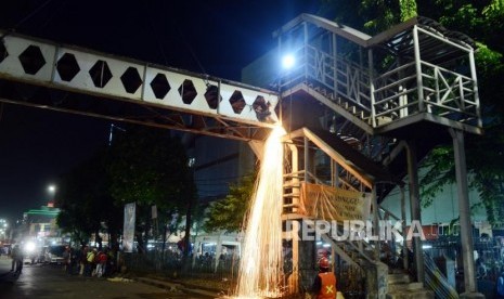 Pekerja saat membongkar Jembatan Penyeberangan Orang (JPO) yang rusak di Pasar Minggu, Jakarta, Sabtu (6/4) dini hari. Pembongkaran itu dilakukan untuk proyek revitalisasi JPO pada Mei mendatang yang nantinya akan didesain dengan gaya futuristik menggunakan dana kompensasi Koefisien Lantai Bangunan (KLB).