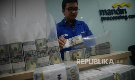 Karyawan menghitung tumpukan uang dolar Amerika Serikat di Cash Center Bank Mandiri, Jakarta, Senin (23/7).