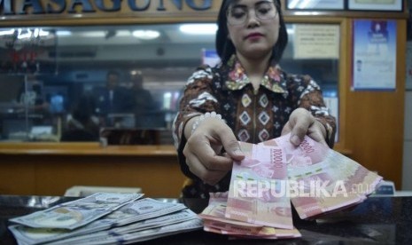 Petugas menghitung mata uang rupiah dan dolar AS di salah satu tempat penukaran uang di Jakarta, Jumat (9/11).