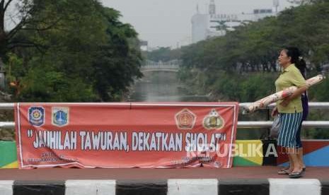 Warga melintas di dekat spanduk bertuliskan himbauan stop tawuran di Kawasan Pasar Rumput, Jakarta, Rabu (29/8).