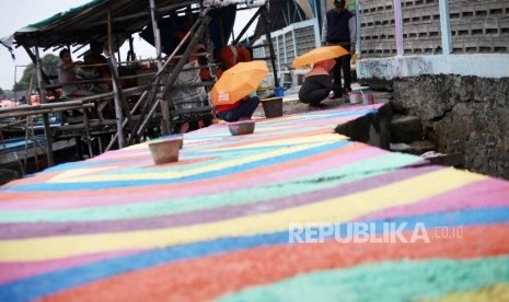 Warga mengecat jalan di kawasan kampung nelayan Kamal Muara, Jakarta, Kamis (15/3).