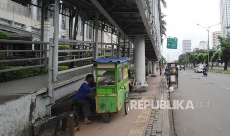 Pedagang berjualan di trotoar di kawasan Jalan Jendral Sudirman, Jakarta Pusat, Ahad (17/12).