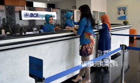 Petugas melayani transaksi nasabah di kantor layanan BCA Syariah, Jakarta, Selasa (6/11).