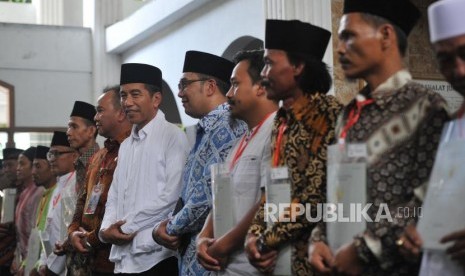 Presiden Joko Widodo (kiri) berfoto bersama seusia memberikan sertifikat tanah wakaf ke warga saat berkunjung ke Pondok Pesantren Al-Ittihad, Cianjur, Jumat (8/2).