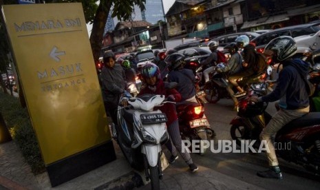 Pengendara motor mendorong motornya melalui trotoar saat terjadi kemacetan di kawasan Pejompongan, Jakarta, Selasa (24/9).