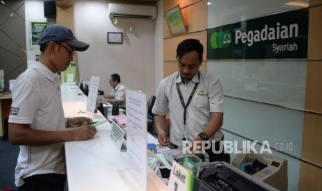 Petugas melayani nasabah ketika bertransaksi di kantor pelayanan Pegadaian Syariah.