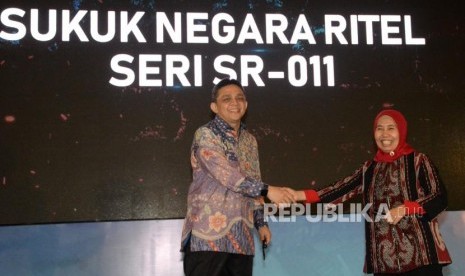 Direktur Jenderal Pengelolaan Pembiayaan dan Risiko Kementerian Keuangan Luky Alfirman (kiri) berjabat tangan dengan Direktur Pembiayaan Syariah Direktorat Jenderal Pengelolaan Pembiayaan dan Risiko Kementerian Keuangan Dwi Irianti Hadiningdyah pada peluncuran Sukuk Negara Ritel Seri SR-011 di Jakarta, Jumat (1/3).