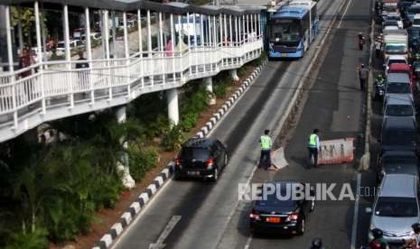 Kendaran mobil dipaksa berjalan mundur saat menerobos sekaligus melawan arah jalur Transjakarta di Kawasan Jalan Matraman, Jakarta, Selasa (4/9).