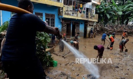 Sejumlah warga beserta petugas gabungan saat membersihkan lumpur sisa banjir di kawasan Rawajati, Jakarta, Ahad (28/4).