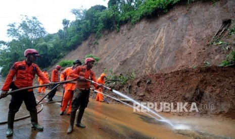 Petugas gabungan menyiram air saat evakuasi longsor di Jalur Utama Puncak, Bogor, Jawa Barat, Senin (5/2).