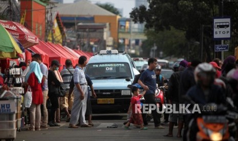 Warga bejalan didepan kendaraan angkutan kota (angkot) jurusan Tanah Abang yang melintas di Jalan Jatibaru, Tanah Abang, Jakarta, Ahad (4/2).