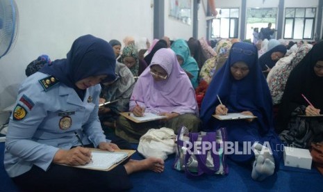 Kepala Lapas Pondok Bambu Ika Yusanti (Kiri) bersama sejumlah warga binaan mengikuti acara menghatamkan Al-Quran tulis dengan metode Follow The Line di Aula Lembaga Pemasyarakatan Perempuan Kelas II A, Pondok Bambu, Jakarta, Kamis (15/2).