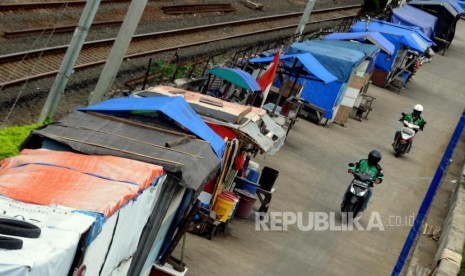 Pengendara motor melintas di kawasan gubuk liar yang berdiri diatas jalan inspeksi Kanal Banjir Barat di Tanah Abang, Jakarta Pusat.