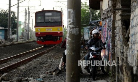 Sejumlah pengendara motor melintasi pinggir rel KRL di kawasan Kedung Badak, Kota Bogor, Jawa Barat, Rabu (19/12).