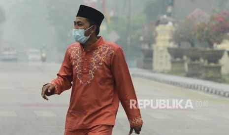 Warga beraktivitas saat asap kebakaran lahan gambut menyelimuti Alun-alun Kabupaten Siak, Riau, Kamis (12/9).