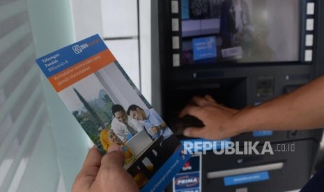 Nasabah membaca brosur usai melakukan transaksi melalui ATM BRI Syariah di Jakarta, Ahad (30/12).